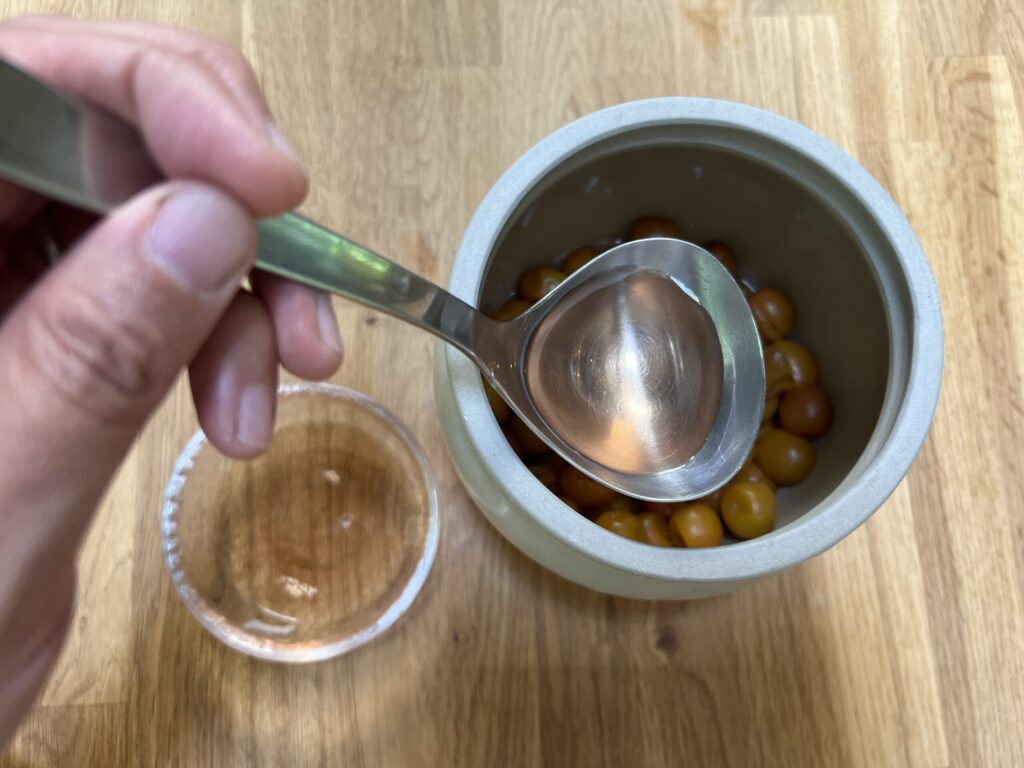 容器から梅酢をすくって取り出す